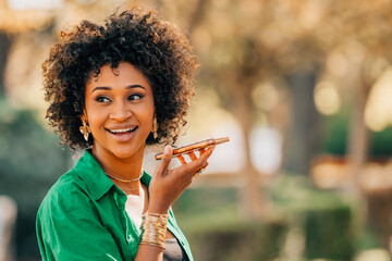 young woman with afro hair sending voice message with mobile phone