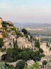 Ancient stone houses built on a rocky cliff surrounded by greenery and valley views