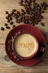 Hello New 2026 Year. Cup of coffee with numbers and roasted beans on woden table, top view