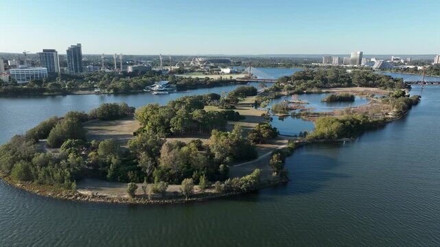 Aerial view of Heirisson Island Kangaroo Sanctuary, a vibrant contrast of lush greenery and tranquil waters, nestled near a modern cityscape, Perth, Western Australia, Australia.
