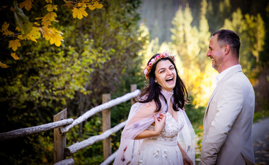 Fototapeta premium happy bride and groom with their dog in beautiful autumn scenery
