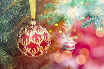 Christmas balls hanging on fir tree branch and bokeh lights on red background
