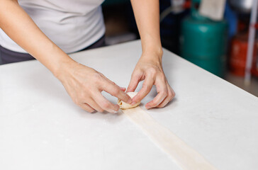 Close-up hand of asian young woman rolling dough into rolls for homemade bread cooking on table in kitchen home, preparation ingredients desserts process making buns manually bakery baking concept.