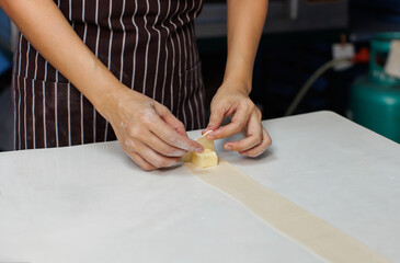 Close-up hand of asian young woman rolling dough into rolls with butter for homemade bread cooking on table in kitchen home, preparation ingredients desserts process making buns manually bakery baking