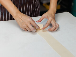 Close-up hand of asian young woman rolling dough into rolls with butter for homemade bread cooking...