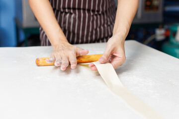 Close-up hand of asian young woman rolling dough into rolls with butter for homemade bread cooking on table in kitchen home, preparation ingredients desserts process making buns manually bakery baking