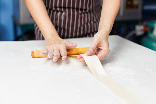 Close-up hand of asian young woman rolling dough into rolls with butter for homemade bread cooking on table in kitchen home, preparation ingredients desserts process making buns manually bakery baking - Powered by Adobe