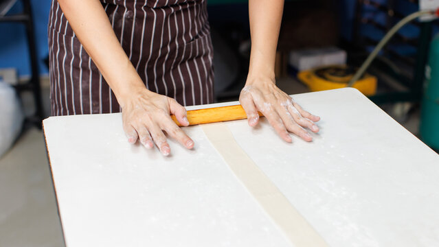 Close-up hand of asian young woman rolling dough into rolls with butter for homemade bread cooking on table in kitchen home, preparation ingredients desserts process making buns manually bakery baking