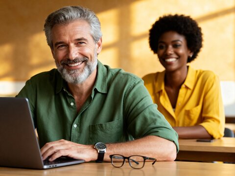 smiling adult students learning together with laptop in classroom