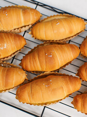 Top view of freshly baked salted butter roll bread on baking wire rack tray, Golden brown texture, homemade bakery concept, warm delicious pastry background, ready to serve buns in small local kitchen