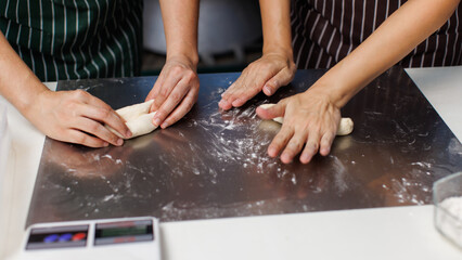 Close up hands of asian woman baker preparing round fresh dough balls on metal plate table for bread pastry making, Homemade bakery process showing soft dough texture, step baking in kitchen workspace