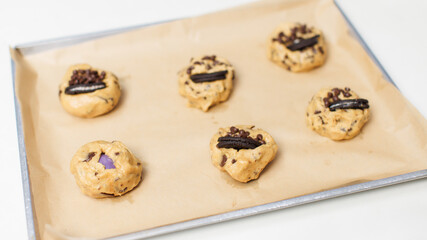 Homemade decorating yummy soft cookies, raw golden dough topped chocolate chips biscuits onto baking sheet tray ready to bake step process showing dessert bakery preparation delicious taste freshly.