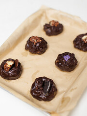 Homemade decorating yummy soft cookies, raw dark dough topped chocolate chips biscuits onto baking sheet tray ready to bake step process showing dessert bakery preparation delicious taste freshly.