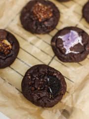 Close up freshly baked homemade dark chocolate soft cookies mixed toppings biscuits wafer marshmallow chocolate chips on baking tray parchment paper sheet, Dessert snack bakery yummy delicious tasty.
