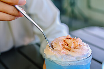 Taking a spoonful of fluffy pink whipped cream from a refreshing Cotton Candy Ice frappe (butterfly pea tea, raspberry, milk)