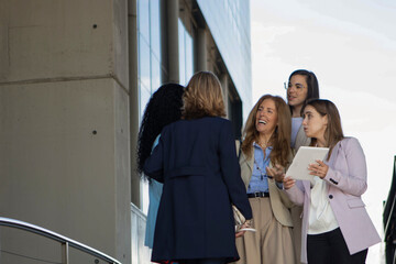 Fototapeta premium Group of women engaging in discussion outside a modern building in an urban setting during late afternoon