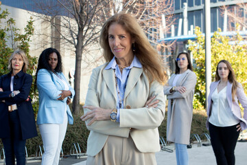 Group of confident women in business attire standing outdoors in a modern urban setting during daylight
