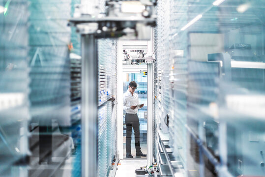 Businessperson with tablet in automated warehouse production hall