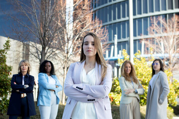 Group of confident women in business attire standing outdoors in a modern urban setting during daylight