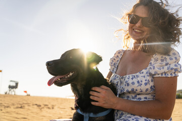 Woman with dog on the beach in summer sunshine