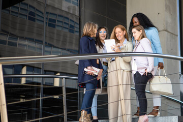 Group of professional women discussing plans at a modern building during the afternoon