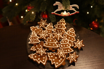 a plate of gingerbread cookies in the shape of Christmas trees and stars, decorated with white...