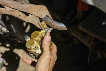 Focused mechanic hand installing golden motorcycle brake caliper during maintenance repair. Close up view of person working on bike part in garage, showcasing skill and precision