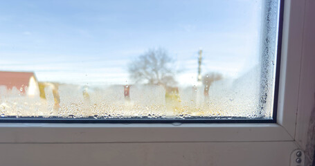 Condensation Droplets on Window Sill with Blurry View of House and Tree on Sunny Day