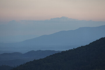 Serene blue mountain landscape at dawn, scenic view showing layers of misty hill. beautiful, calm atmosphere provides peaceful and tranquil nature background
