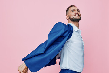 A professional man in a blue suit strikes a dynamic pose against a solid pink background, conveying...