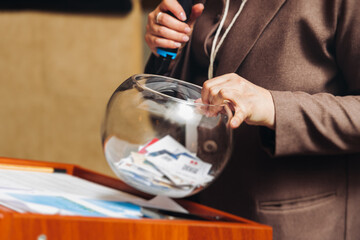 Process of prize drawings, extracting a winning numbers of lottery machine, raffle drum with bingo balls, bingo machine and winning tickets on event with a female host, hands on lottery machine