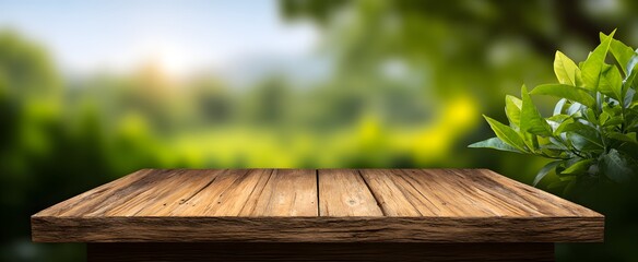 Naklejka premium The wooden table surface bathed in gentle sunlight with a vibrant blurred green nature backdrop