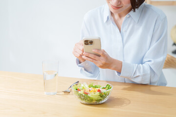 サラダを食べる女性・スマホ