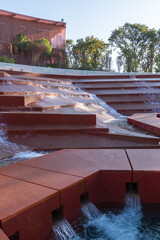 Architectural space with  red-colored cascading terraces and flowing water, creating stepped waterfall effect. Water amphitheater or canyon in Krasnodar's city park, or Galitsky Park.