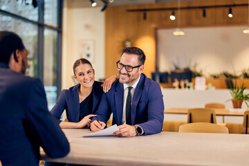 Professional Business Meeting Between Colleagues In Modern Office Signing Documents And Smiling Together At Table