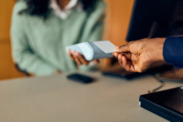 African-American Man Handing Card To Payment Terminal During Transaction At Office