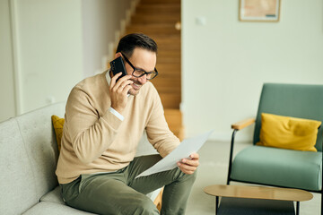 Obraz premium Man On Phone With Paper In Cozy Living Room For Home Office Setup