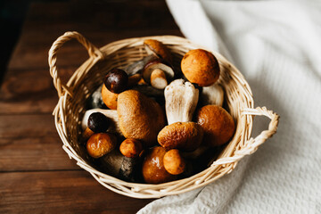 Fresh boletus mushrooms in woven basket on wooden table