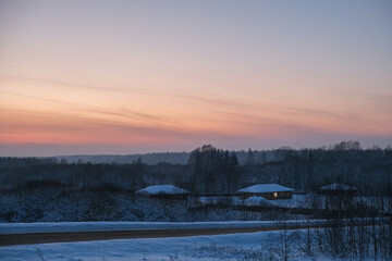 winter sunset over snowy village landscape with calm nature