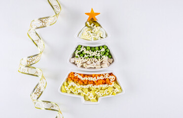 Traditional Russian olivier salad ingredients displayed in creative holiday tree shaped bowls