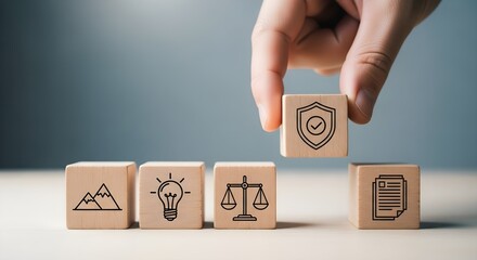Hand places wooden block with shield icon on top of other blocks representing concepts