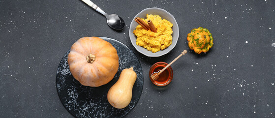 Bowl of tasty millet porridge with pumpkin and honey on black background