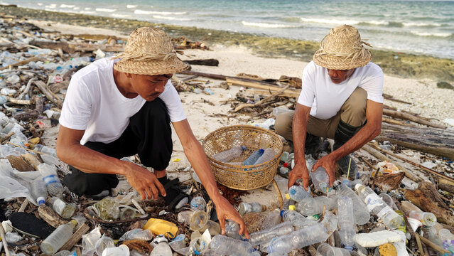 Indonesian men collecting plastic bottles on a polluted bean in indonesia, waste pickers, informal waste management, picking up waste for recycling, asia, ocean pollution