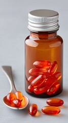 Amber Glass Medicine Bottle Filled With Orange Gel Capsules Next To A Silver Spoon With Capsules On A Textured Gray Surface Studio Lighting