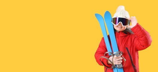 Little girl with skis on yellow background with space for text