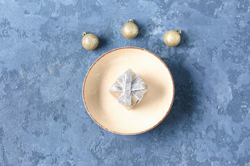 Beautiful table setting with Christmas balls and gift box on blue background