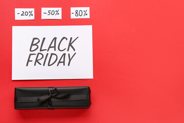 Greeting card with text BLACK FRIDAY, gift box and discount tags on red background