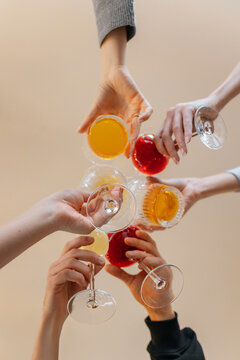 Bottom view of a group of friends making cheers with cocktails during a celebration in a restaurant. Friends relaxing at a bar with alcoholic drinks