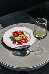 Dessert napoleon with pistachio, decorated with strawberries on a table with a glass of prosecco and white wine. Delicious snack with sweet pastries
