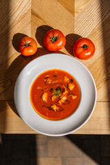 Tomato cream soup in a plate with tomatoes nearby. Italian cuisine with tomatoes